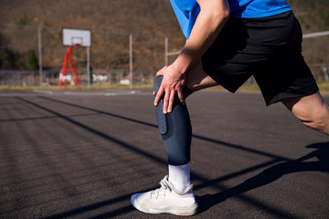 Fototapeta premium Injured basketball player holding his leg in pain