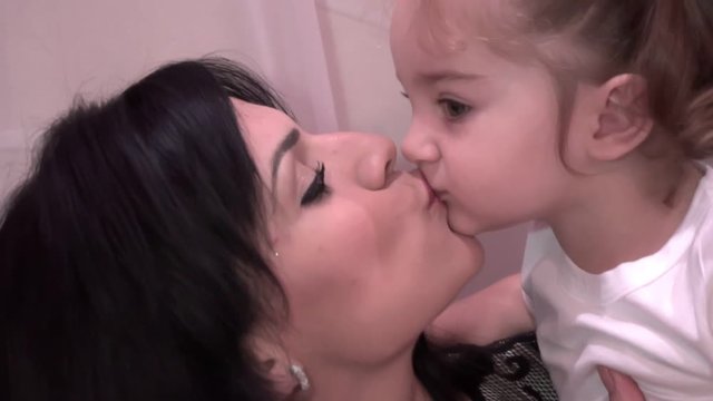 Baby daughter kisses on the lips with her young mother