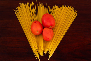 Top view of three tomatoes over a bed of spaghetti