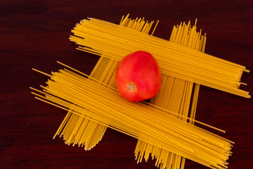 Top view of one tomato over a hashtag made of  spaghetti