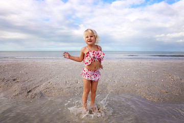 Cute Little Child Splashing and Playing in the Water on the Beach by the Ocean