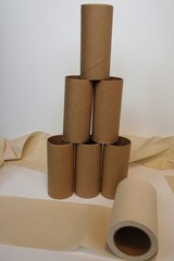 leere Klopapierrollen zu einem Turm gestapelt und eine fast abgerollte Rolle vor weißem Hintergrund