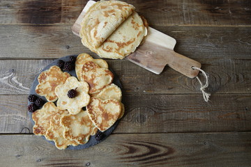 pancakes in the shape of a heart and flowers and pancakes on a board on a rustic wooden table with space for text. Flat lay. Top view.
