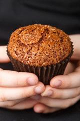 Homemade chocolate muffin with caramel (sugar) crust in the children's hands. Dessert for gourmet. Selective focus