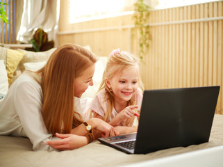 Happy family mother with daughter using computer laptop at home, modern lifestyle