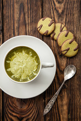 cup of hot matcha green tea latte and green cookies on wood background