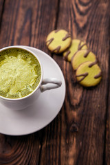 one cup of hot matcha green tea latte and green cookies on wood background