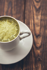 one cup of hot matcha green tea latte, close up on wood background