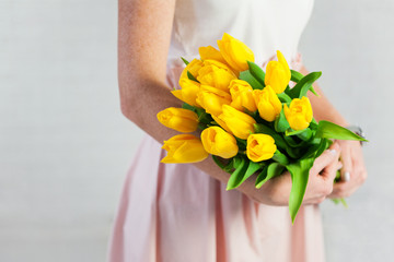 female hands holding bouquet of yellow tulips