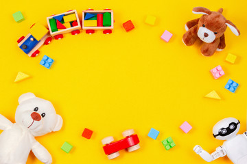 Kids toys background. White teddy bear, wooden train, toy car, robot, colorful blocks on yellow background
