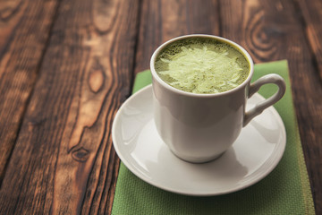 one cup of hot matcha green tea latte on wood background