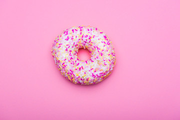 Donut with colorful sprinkles on a pink background