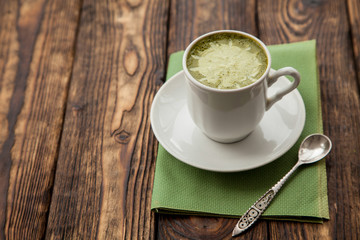 one cup of hot matcha green tea latte on wood background