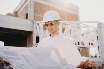 Young male engineer looking on the project to see how work goes on the building that are in work.