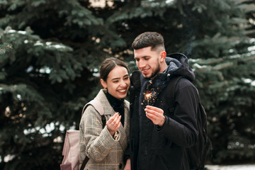 Fototapeta premium A young couple laughing with bengal lights in the hands