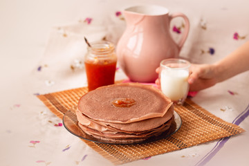 Many Russian-style thin pancakes with crispy crust served with cream and milk.