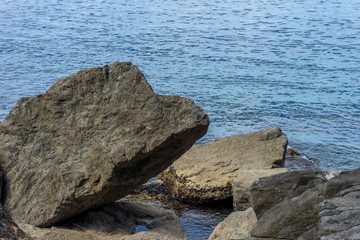 Italy,Cinque Terre,Riomaggiore, a man sitting on a rock next to a body of water