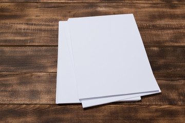 Blank paper notebook on brown wooden table background. Top view with copy space