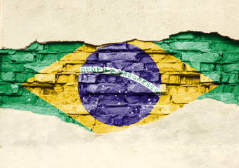 National flag of Brazilia on a brick background. Brick wall with partially destroyed plaster, background or texture.
