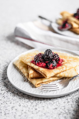 Pancakes with berries and honey on a gray background. Pancake week. Delicious breakfast of pancakes with jam.