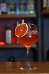 Glass of orange cocktail decorated with orange at bar counter background