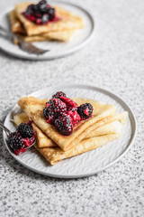Pancakes with berries and honey on a gray background. Pancake week. Delicious breakfast of pancakes with jam.