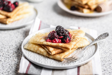 Pancakes with berries and honey on a gray background. Pancake week. Delicious breakfast of pancakes with jam.