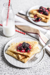 Pancakes with berries and honey on a gray background. Pancake week. Delicious breakfast of pancakes with jam.