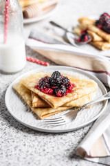 Pancakes with berries and honey on a gray background. Pancake week. Delicious breakfast of pancakes with jam.