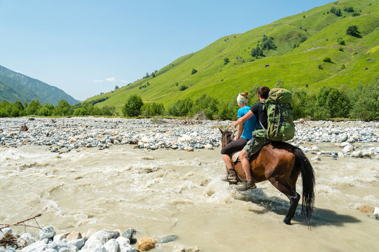 Girl wading dangerous river a on horse, Adischala river, Adishi, Svaneti, Caucasus mountains,Georgia