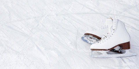 white figure skates and copy space over ice background with marks from skating