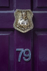 House number 79 with the seventy nine in silver lettering under a bronze plaque showing a woman...