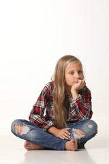 Girl with long blond hair sits on the floor. White background