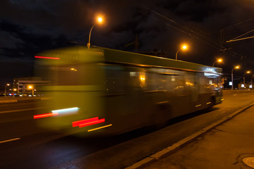 The motion of a blurred bus on the avenue in the evening.