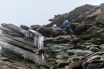 Alpinist in extremely dangerous frozen rocky section, risk and hazard in high mountains, Alps, France