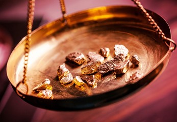 Small gold nuggets in an antique measuring scale