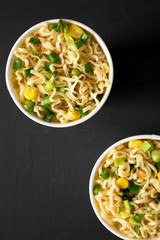 Tasty instant noodles with beef flavoring in a cup over black table. Flat lay, from above, overhead. Close-up.