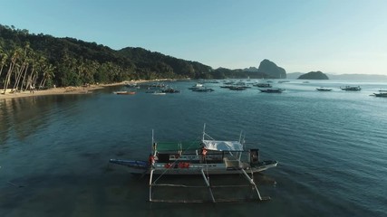 Aerial drone view of boats anchored in the bay with clear and turquoise water on the sunset. Boat and yacht in the tropical lagoon. Tropical landscape. El Nido, Palawan island, Philippines.