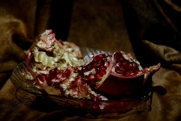 Ripe red garnet in a glass platter on a brown background