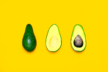 Ripe sliced avocado on bright yellow background top view. Creative food composition Flat lay. Pop art design, tropical summer abstract background with avocado. Green avocadoes pattern, diet concept