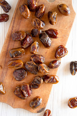 Dried dates on rustic wooden board over white wooden background, top view. From above, overhead, flat lay. Closeup.