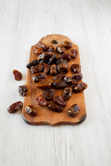 Dried dates on rustic wooden board over white wooden background, low angle view. Closeup.