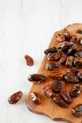 Dried dates on rustic wooden board over white wooden surface, low angle view. Close-up. Copy space.