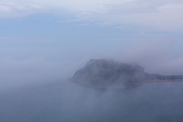 Naklejka na ściany i meble Barrenjoey lighthouse on a hill hidden by thick low clouds over ocean
