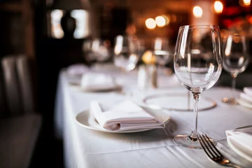 Zelfklevend Fotobehang Een close-up shot van een restauranttafel met servies en wijnglas. Concept van dineren, gastvrijheid en catering. Horizontale afbeelding met vrije ruimte voor tekst. © Olga