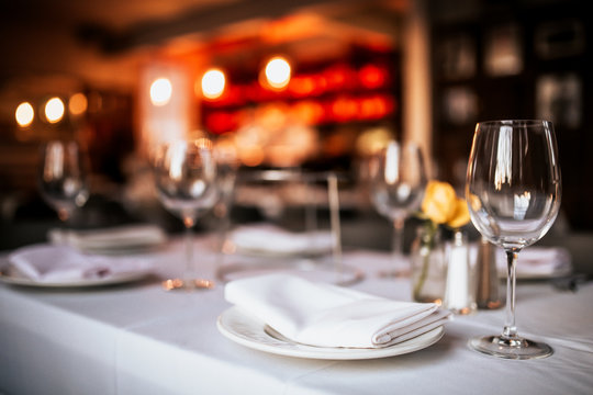 A close up shot of a restaurant table set up with tableware and wine glass. Concept of dining, hospitality and catering. Horizontal image with free space for text.