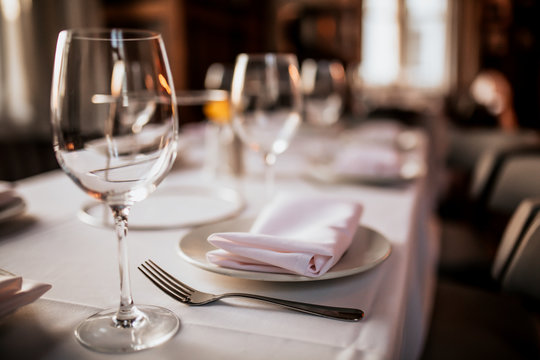 A close up shot of a restaurant table set up with tableware and wine glass. Concept of dining, hospitality and catering. Horizontal image with free space for text.