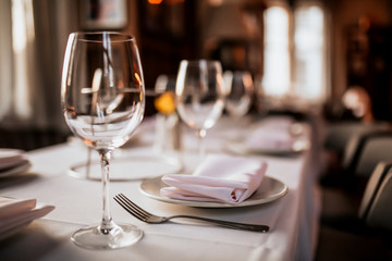 A close up shot of a restaurant table set up with tableware and wine glass. Concept of dining,...