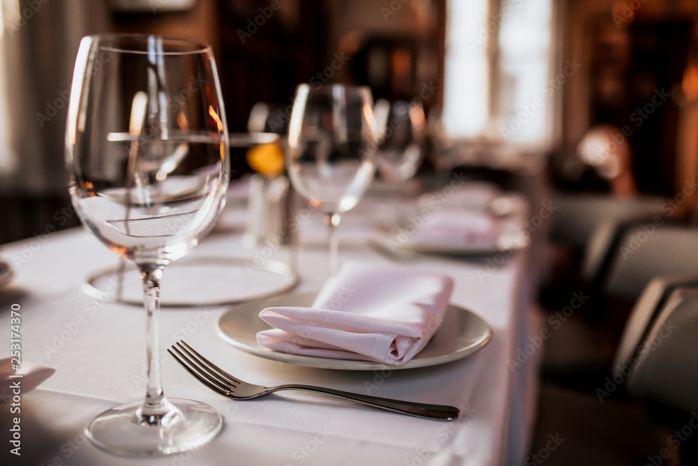 Wall mural a close up shot of a restaurant table set up with tableware and wine glass. concept of dining, hospi