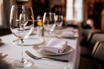 A close up shot of a restaurant table set up with tableware and wine glass. Concept of dining, hospitality and catering. Horizontal image with free space for text. - obrazy, fototapety, plakaty